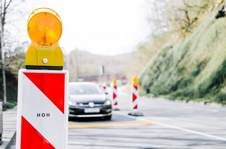 Verkehrsleitkegel Nahaufnahme vor Auto mit gelber Fahrbahnmarkierung